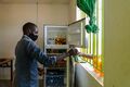 Simon Dumba a computer instructor at Icon Electronics Centre serves soft drinks, chilled in a solar powered fridge, to a customer at Ofua 3, Uriama Sub-County in Terego District, on October 1, 2021.